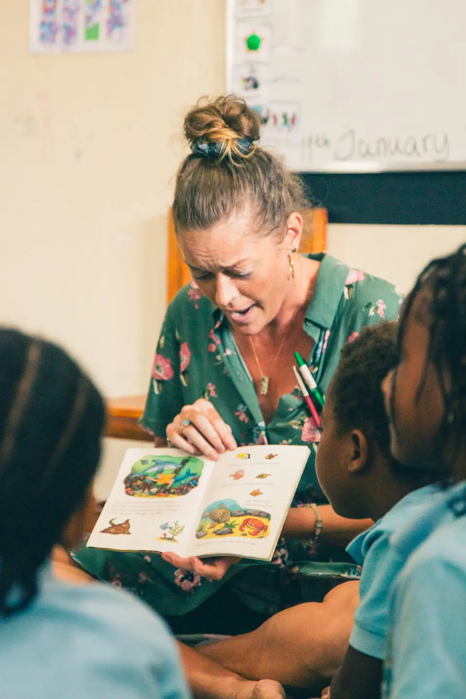 South East Coast International School Zanzibar teacher holding a book surrounded with kids in a classroom