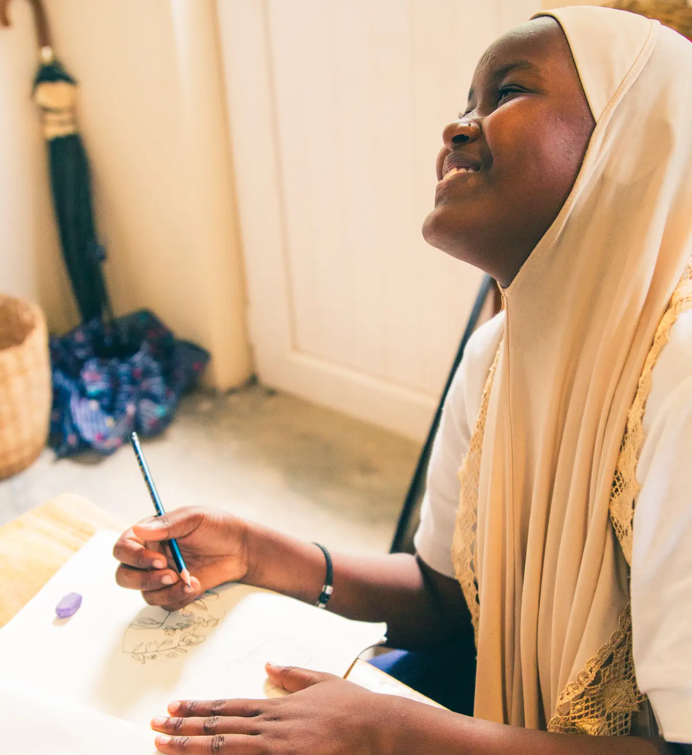 South East Coast International School Zanzibar pupil smilling whilst sat at a desk with a pencil and textbook